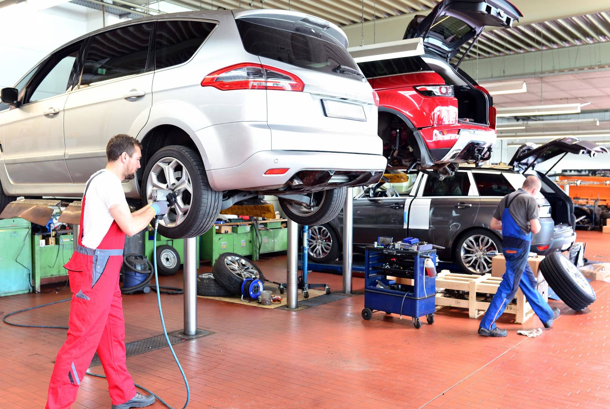 mécaniciens en garage changeant et vérifiant la pression des pneus de voitures